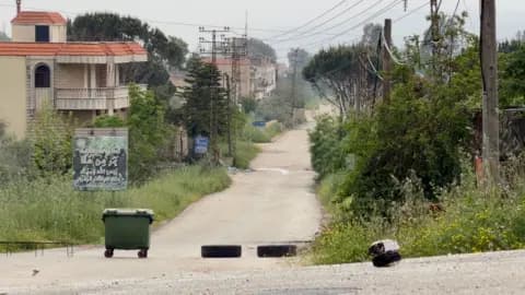 A large rubbish bin and two tyres on an empty road in southern Lebanon, near territory occupied by Israeli forces