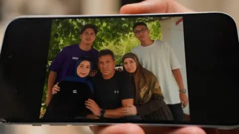 A person holds a phone showing a photo of five members of a family who were killed in an Israeli air strike in Saksakiyeh, southern Lebanon