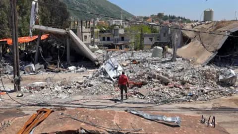 A man stands next to a destroyed building in Lebanon
