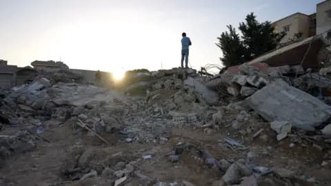 A man stands on top of rubble from a building destroyed in an Israeli air strike in Saksakiyeh, southern Lebanon, which killed nine members of one family
