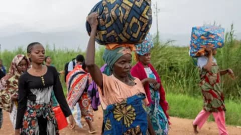 Women - described by Reuters as foreigners - walk on a road with their belongings after rebels seized Uvira city in December